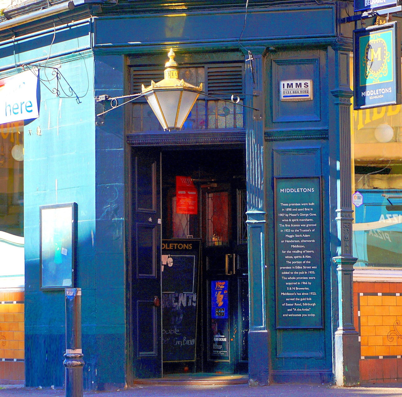 Blue painted Victorian storefront with ornate lamp and glass door
