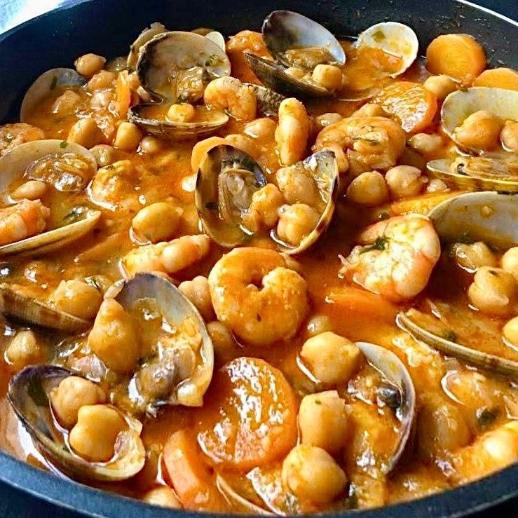 Close-up of chickpeas with shrimp and clams in a red tomato sauce