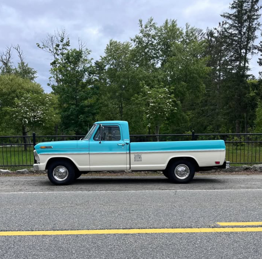 Classic turquoise and white Ford pickup truck parked beside a road