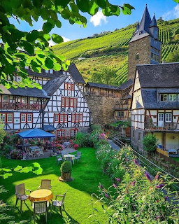 Half-timbered houses and stone tower with garden and vineyard hillside in Bacharach, Germany