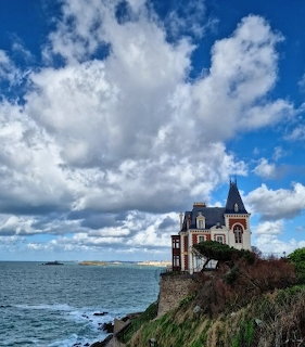 Seaside villa with turret on a cliff above the ocean under dramatic clouds