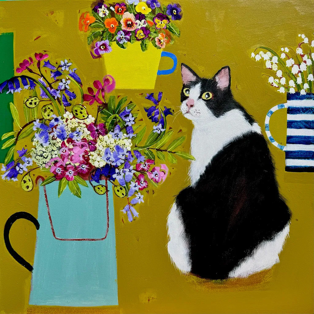 Tuxedo cat sitting next to a turquoise vase of colorful flowers on yellow background