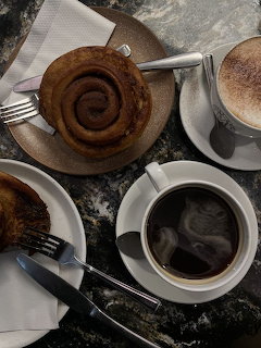 Cinnamon buns with black coffee and a frothy latte on a dark table