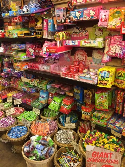 Brightly lit candy shop interior with shelves and baskets full of colorful candies and sweets