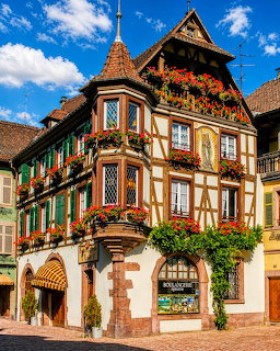 Ornate half-timbered building with red flower boxes and traditional Bavarian architecture on a sunny day