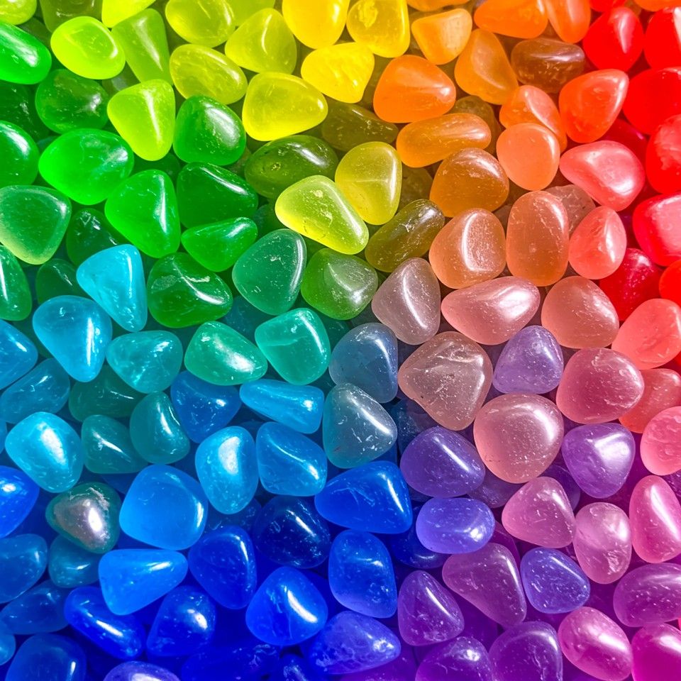 Colorful glass beads arranged in a rainbow gradient from blue and green to red and purple