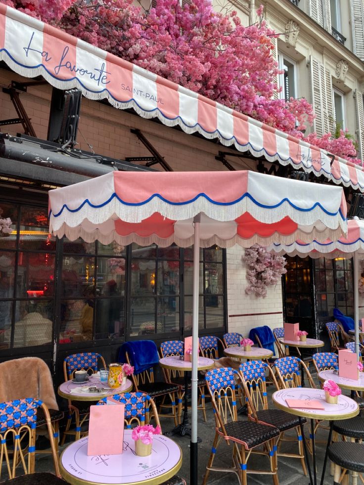 Parisian café exterior with pink striped awning, wicker bistro chairs, and blooming pink flowers above