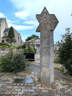 Weathered stone mercat cross with carved Star of David pattern in Scottish town square