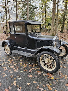 Black 1925 Ford Model T coupe parked outdoors on fallen leaves with trees in background