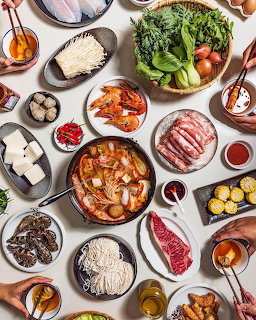 Overhead flatlay of brunch dishes including meats, cheese, salads, and bread on white plates