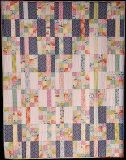 Colorful patchwork quilt with vertical strips of floral and solid fabric in pastel and neutral tones