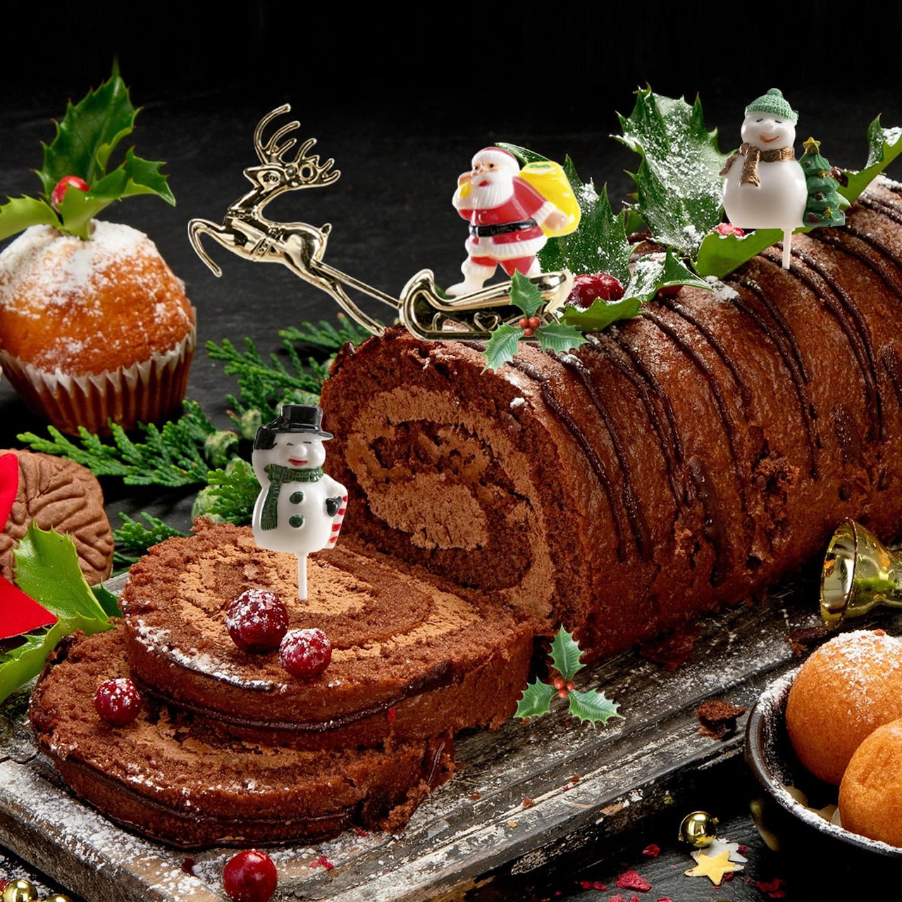 Sliced chocolate yule log cake with Christmas decorations including Santa, holly, and pine branches