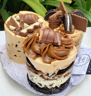 Layered cake with peanut butter frosting topped with chocolate candies and cookies