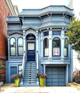 Gray-blue Victorian house with ornate trim, bay windows, front stairs, and garage door