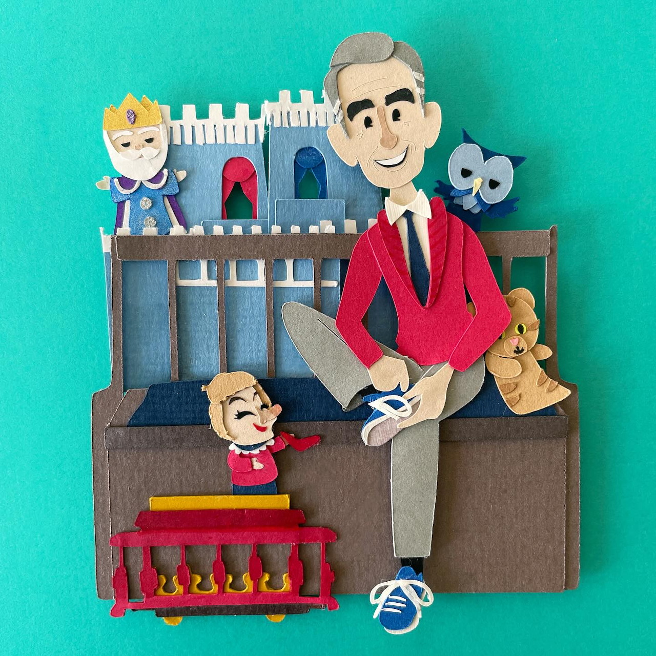 Felt-style Mister Rogers figure with toy trolley, puppets, and castle backdrop on a teal background.