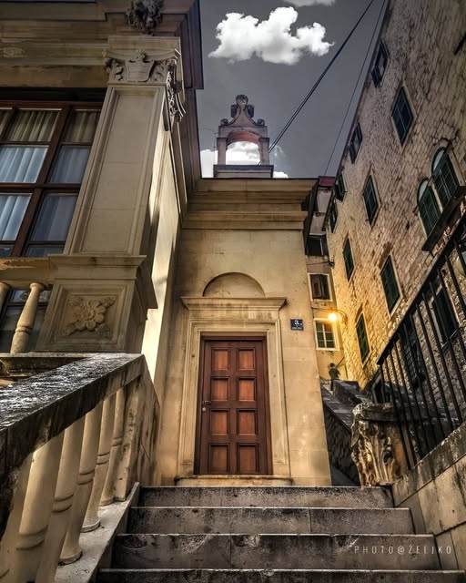 Stone steps and wooden door in Šibenik Croatia old town with clock tower and historic buildings