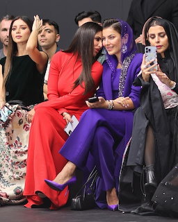Women in colorful formal attire seated at fashion show front row