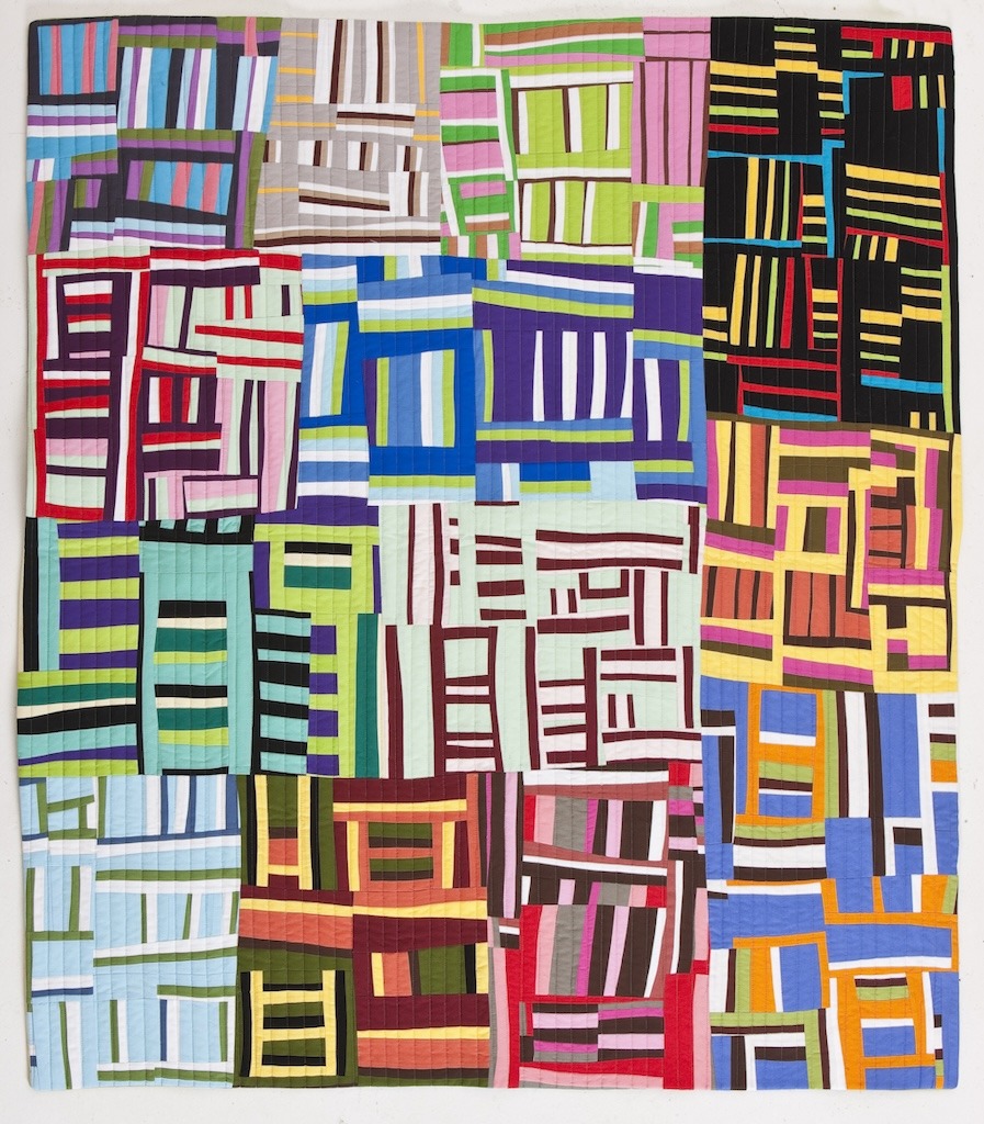 Colorful modern improvisational quilt with geometric striped blocks in various bright colors