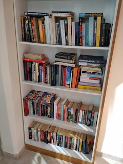 White bookshelf with five shelves filled with colorful books of various sizes
