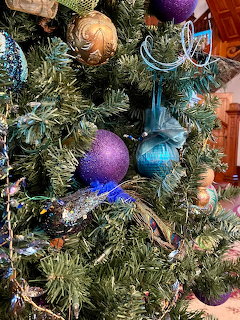 Close-up of Christmas tree with purple and teal ornaments among green branches