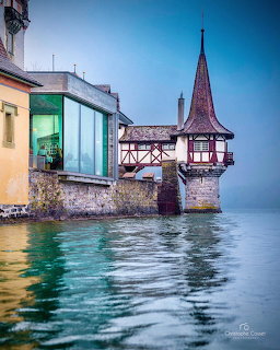 Medieval castle tower with turret beside lake with turquoise water and reflections at twilight