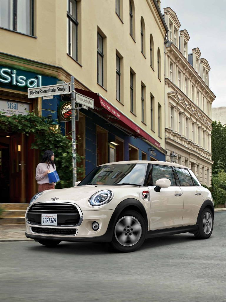 White Mini Cooper parked on cobblestone street with historic buildings