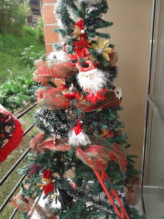 Cat camouflaged in a decorated Christmas tree with red ribbons and ornaments