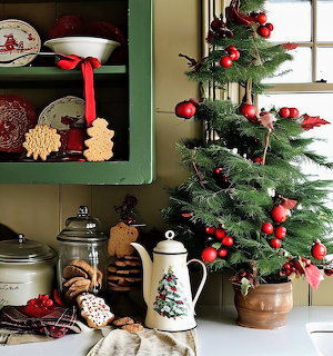 Christmas tree with red ornaments next to vintage coffee pot and cookies on kitchen counter