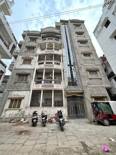 Weathered apartment building with balconies, motorcycles, and a small vehicle on a narrow street