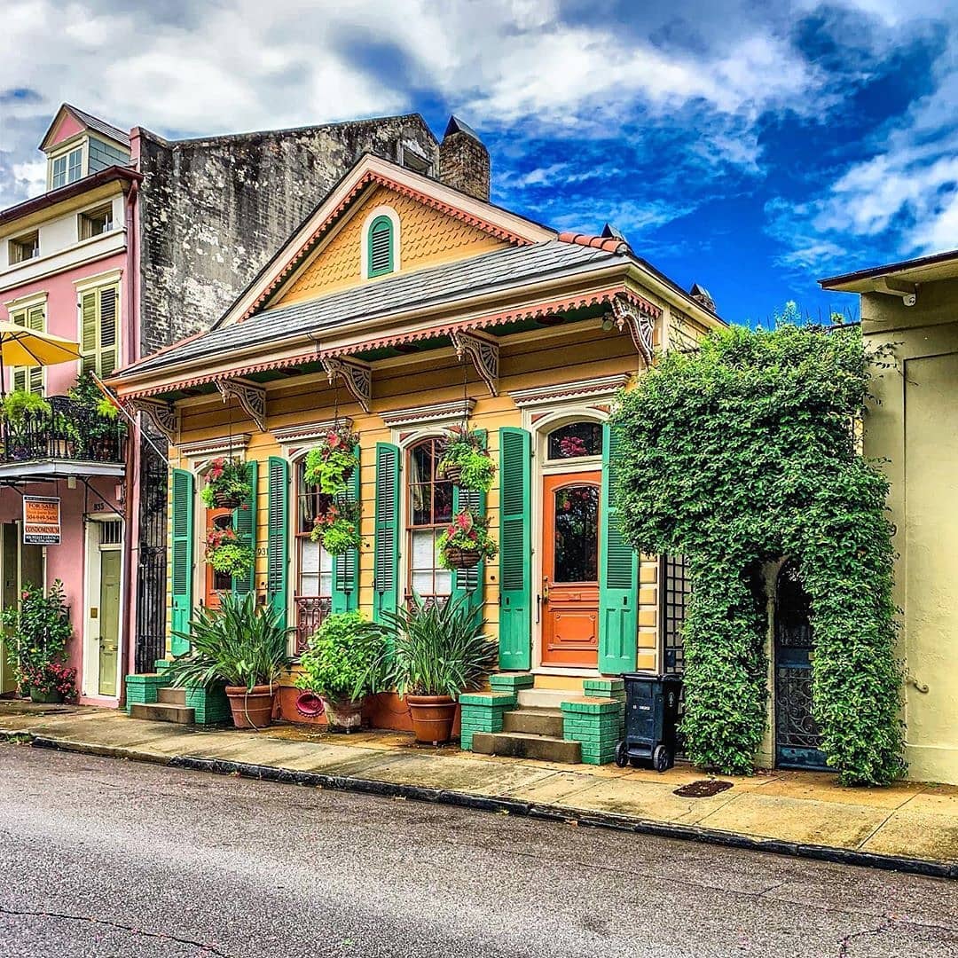 Colorful historic New Orleans homes along a quiet street with potted plants and ornate trim