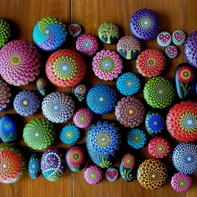 Colorful mandala-painted stones with dot patterns on wooden background