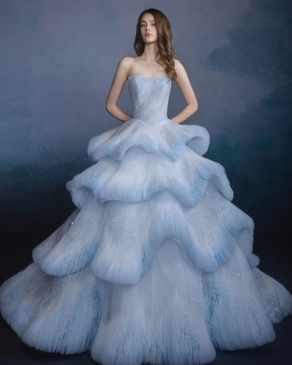 Woman wearing a strapless light blue tiered tulle ball gown with a dramatic voluminous skirt