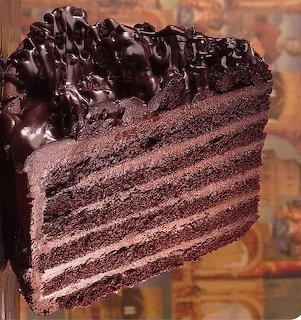 Close-up of a slice of chocolate layer cake with dark chocolate icing