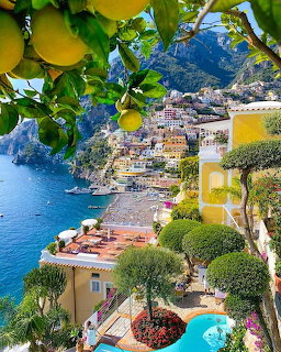 Amalfi Coast village with colorful buildings, lemon tree, turquoise sea, and swimming pool