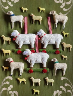 Handcrafted wool sheep ornaments with red gingham ribbon on green patterned fabric background