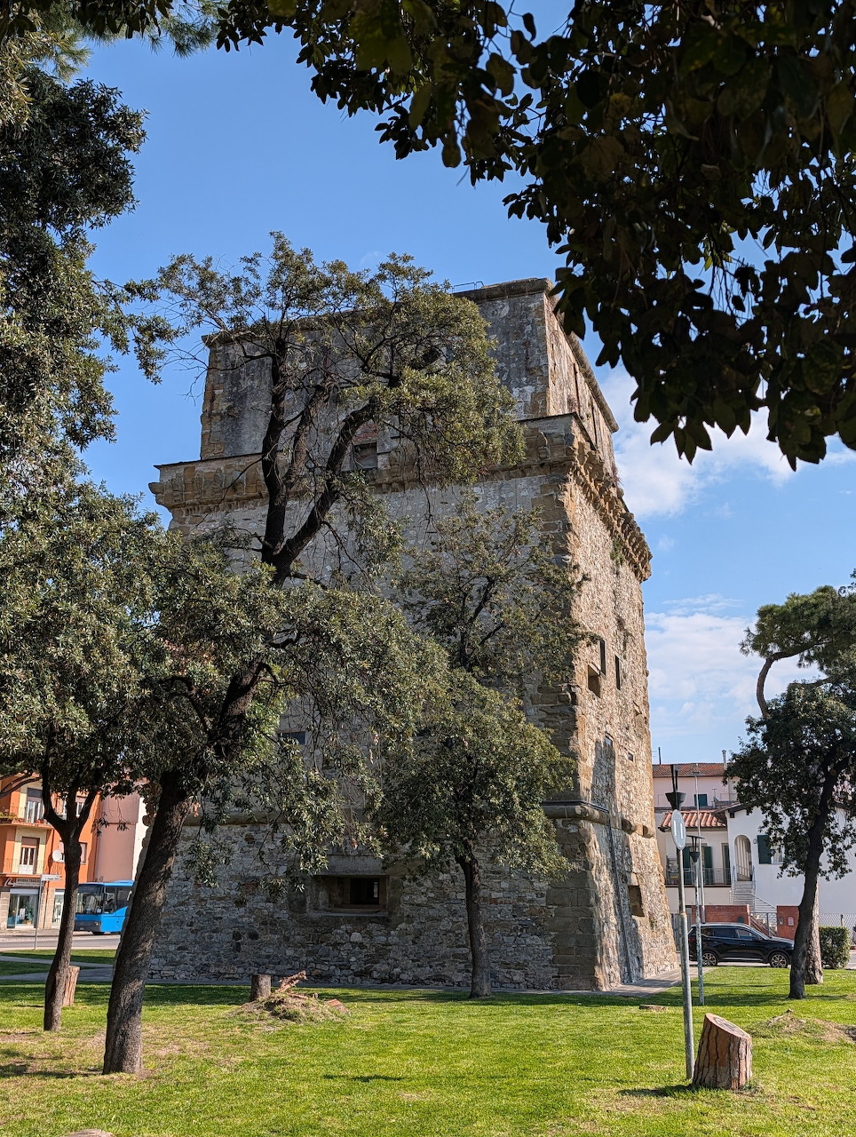 Medieval stone tower with trees in foreground on sunny day