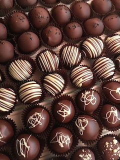 Assorted chocolate truffles with white chocolate drizzle patterns and decorative toppings