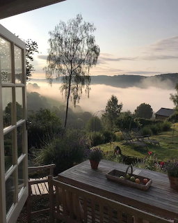 Wooden patio overlooking a misty garden and foggy hills at sunrise