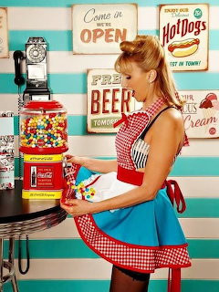 Waitress in red gingham dress holding tray in retro diner with gumball machines and vintage signs