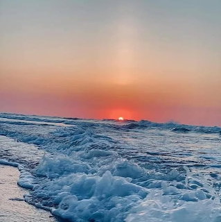 Sunrise over ocean waves with foam and colorful sky at beach