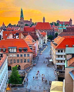 Nuremberg old town skyline with red roofs, church spires, and a cobblestone street at sunset