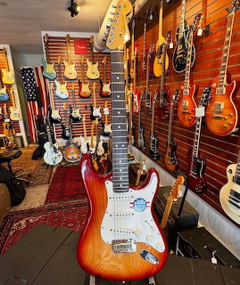 Sunburst electric guitar in a guitar shop with many guitars hanging on the walls