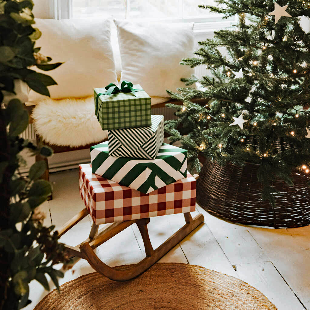 Wrapped Christmas presents on a wooden rocking chair next to a decorated Christmas tree
