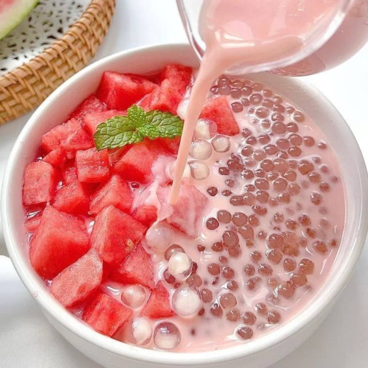 Bowl of watermelon sago with tapioca pearls and milk being poured