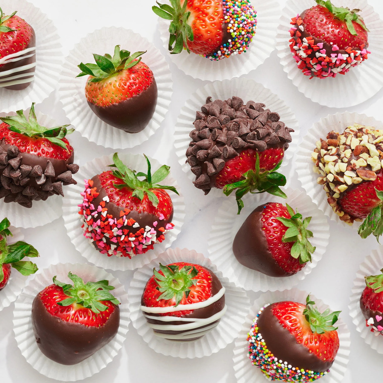 Chocolate covered strawberries with colorful toppings arranged on white paper cups