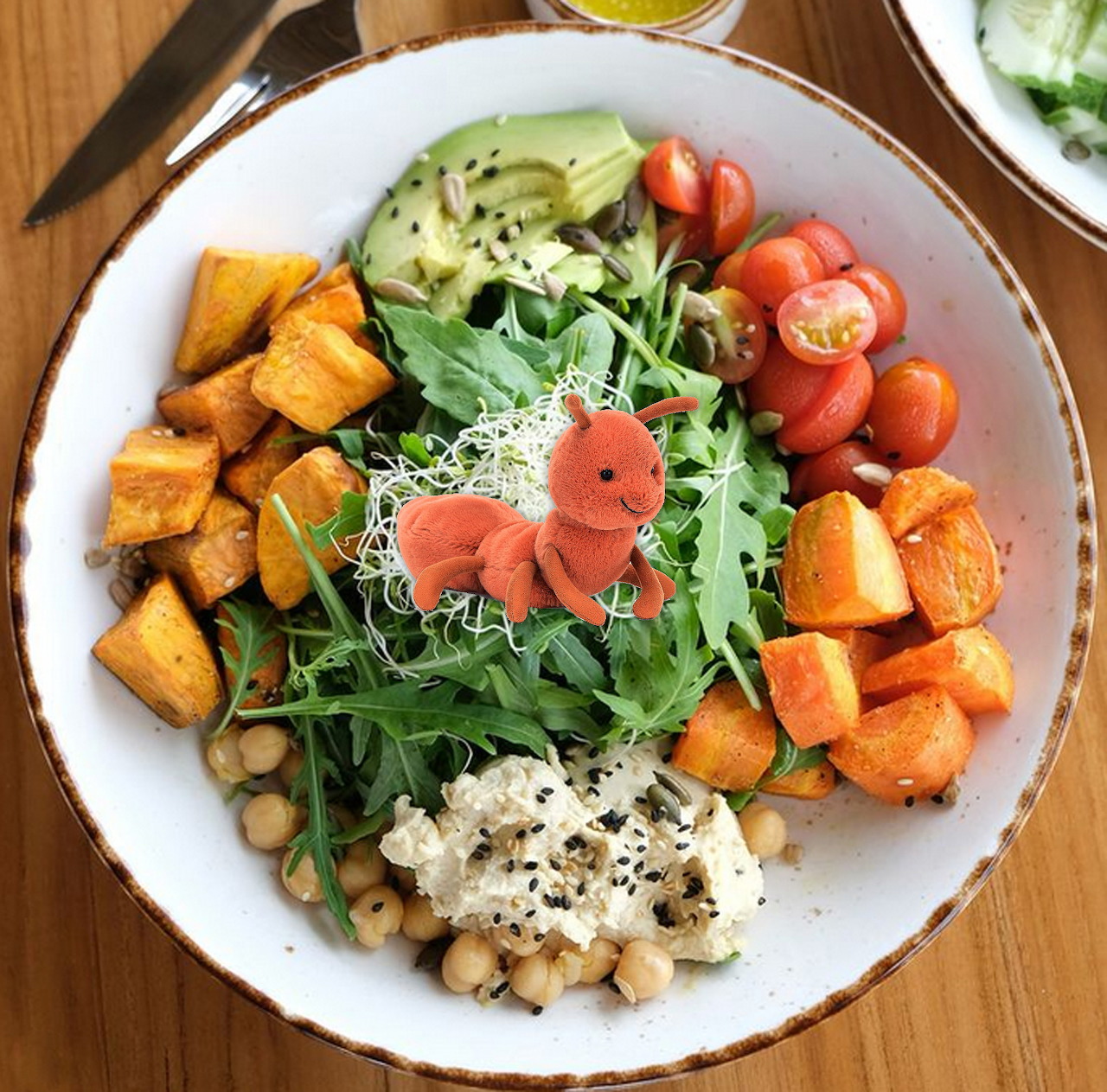 Overhead view of a vibrant Buddha bowl with roasted vegetables, greens, chickpeas, and dressing on wooden table