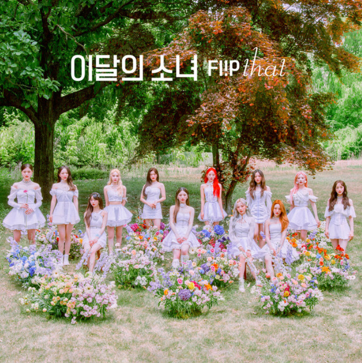 Girl group in white dresses posing among flower beds under a large tree in a garden