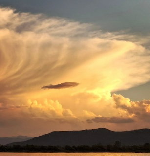Dramatic golden clouds at sunset above dark mountain silhouettes