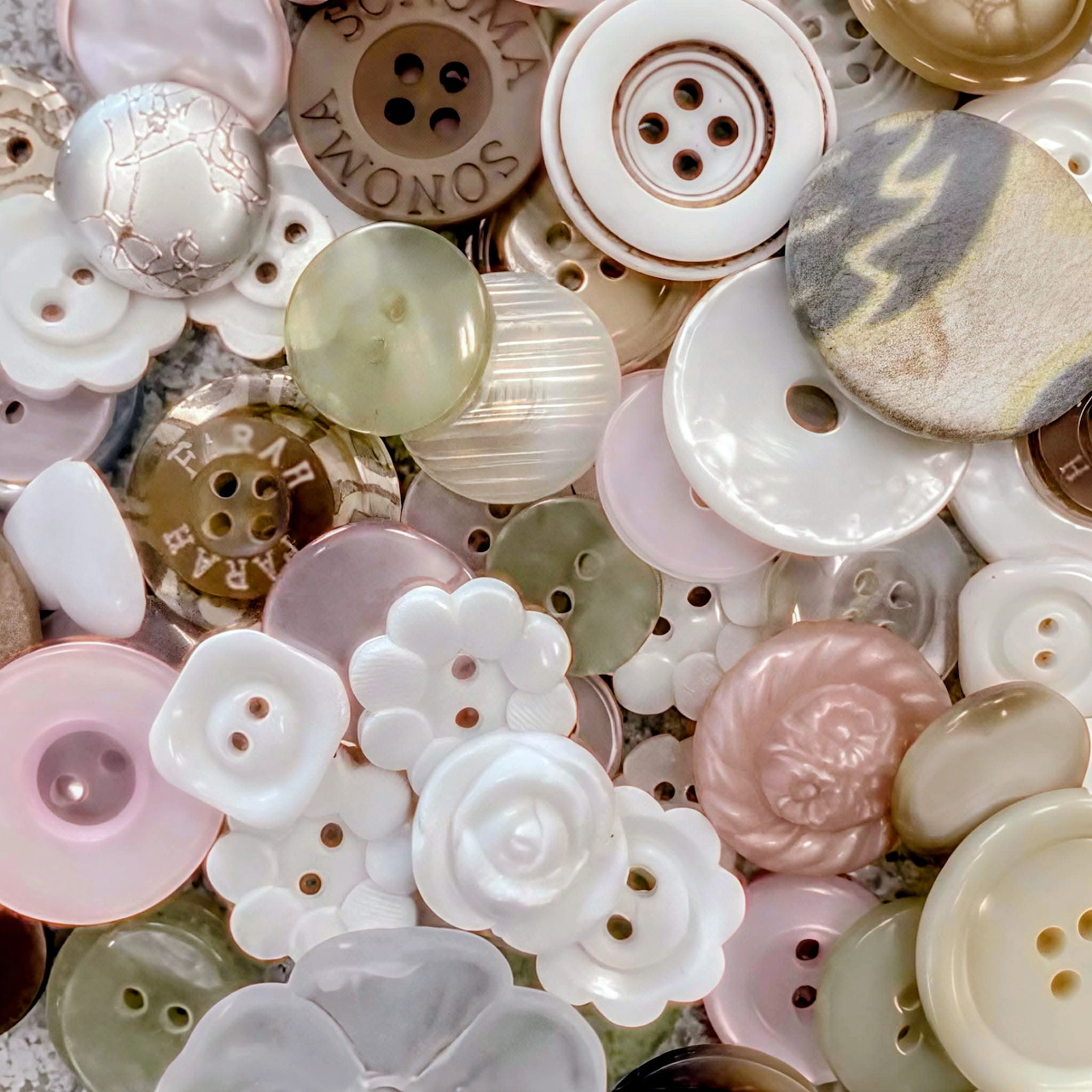 Close-up of assorted vintage pastel buttons in pink, white, cream, and beige