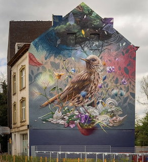 Colorful street art mural of bird with flowers painted on building side in Maastricht